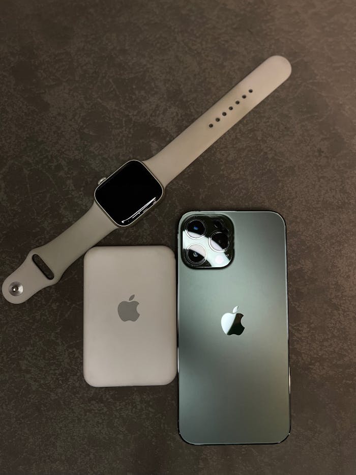 Flat lay of smartwatch, smartphone, and wireless charger on a gray background.